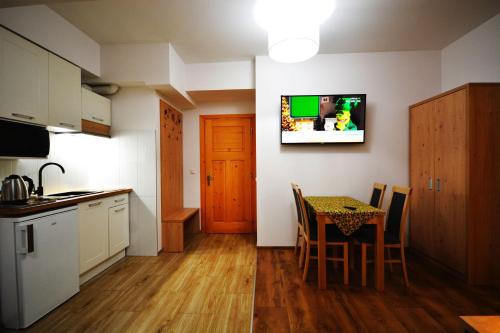 a kitchen with a table and a television on a wall at Apartamenty Willa Anna in Poronin
