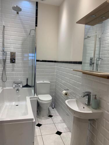 a bathroom with a toilet and a tub and a sink at Caroline's House in Swanage