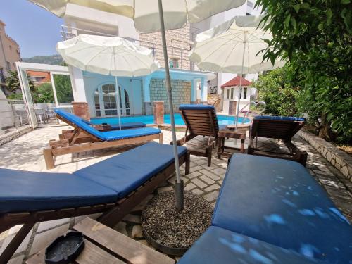 a patio with chairs and umbrellas and a pool at Villa Golf 2 in Budva