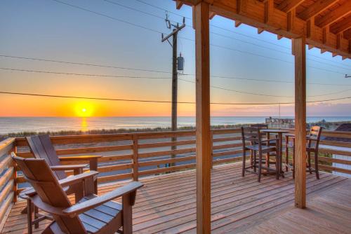 une terrasse avec des chaises et une table sur la plage au coucher du soleil dans l'établissement 4115 - Coastal Cottage, à Kitty Hawk