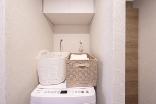 a bathroom with a toilet with a basket on top at ZAITO Waseda Terra Hotel in Tokyo