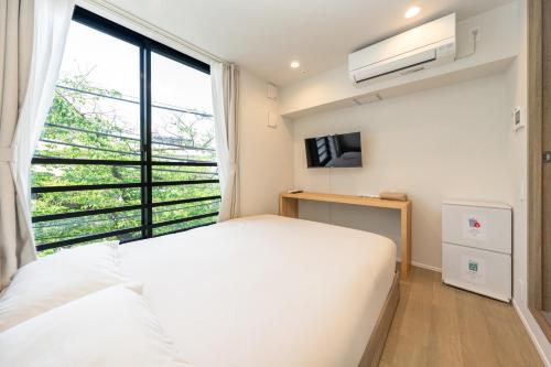 a bedroom with a white bed and a large window at ZAITO Waseda Terra Hotel in Tokyo