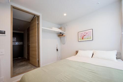 a small bedroom with a bed and a mirror at ZAITO Waseda Terra Hotel in Tokyo