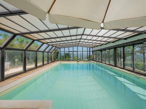 an indoor swimming pool with glass walls and a ceiling at Luxury large pool villa in Tolentino in Tolentino