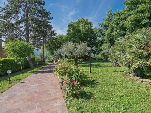 a brick path in a park with flowers and trees at Marche Hilltop Villa with Pool in Tolentino