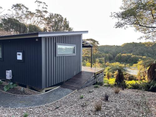 a black tiny house with a wooden deck at Beaks and Feathers Boutique Accommodation on Stewart Island in Stewart Island