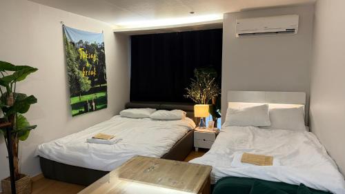 a room with two beds and a table in it at Kozy House in Gangnam in Seoul