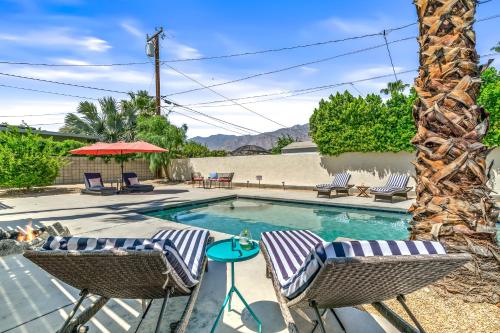 a swimming pool with two chairs and a table at Palm Springs Home with a Resort Style Backyard -Joy pool hot tub views in Palm Springs