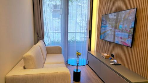 a living room with a couch and a tv at La Green Hotel and Residence in Bang Tao Beach