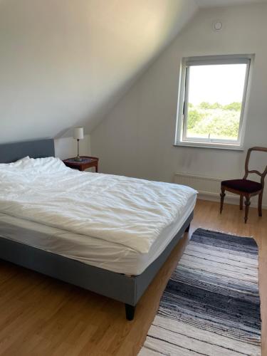 a bedroom with a bed and a window and a chair at Ausås Ängelholm in Ängelholm