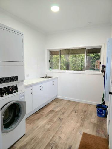 a white laundry room with a washer and dryer at Tanunda Central Cottage in Tanunda