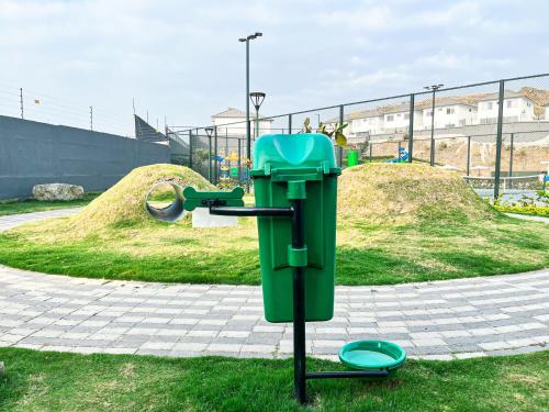 a green trash can in a park with a frisbee at Casa de Lujo, Parking, Piscina, Gym, Juegos in Guayaquil
