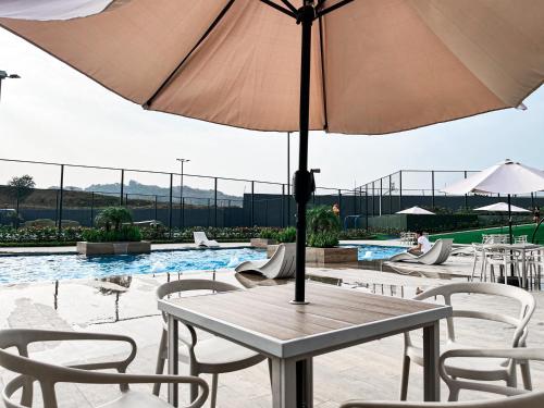 a table with an umbrella in front of a pool at Casa de Lujo, Parking, Piscina, Gym, Juegos in Guayaquil