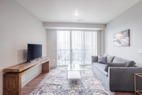 a living room with a couch and a flat screen tv at TWO CozySuites at the Banks with Pool 18 in Cincinnati