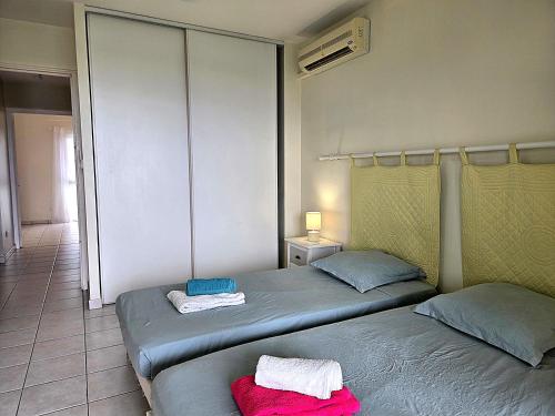 two beds in a room with two towels on them at Orchidée, Spacieux & Vue mer in Les Trois-Îlets