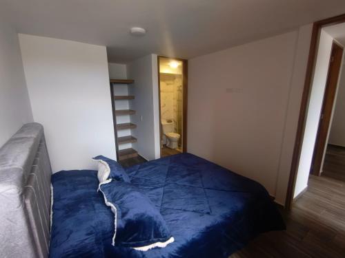 Cómodo Apartamento turístico Paipa في بايبا: غرفة بسرير وبطانية زرقاء
