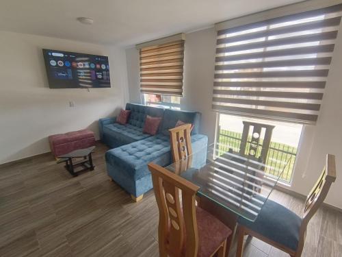 Cómodo Apartamento turístico Paipa في بايبا: غرفة معيشة مع أريكة زرقاء وطاولة