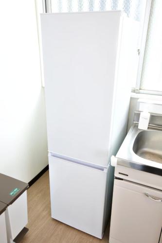 a white refrigerator in a kitchen with a sink at cuculu MAEJIMA 4F in Tomari