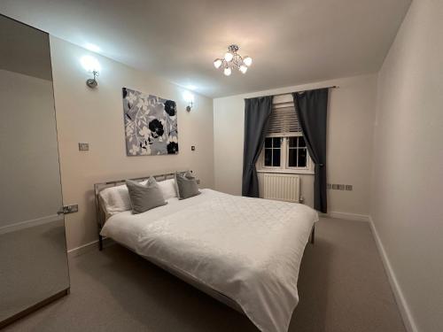 a bedroom with a large white bed and a window at Spacious 3 Bed Apartment in Central Romford just 5 mins to Elizabeth Line for Families Friends and Contractors in Romford