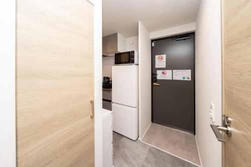 a door leading into a kitchen with a refrigerator at ZAITO Waseda Terra Hotel in Tokyo