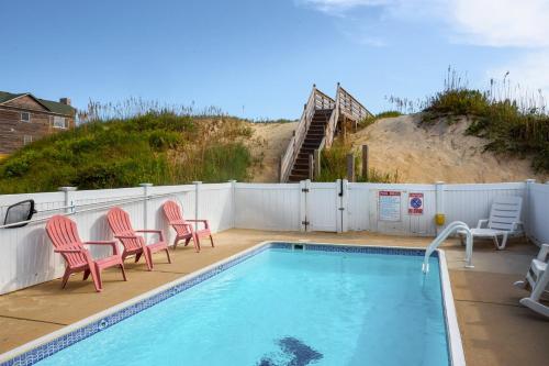 a swimming pool with two chairs and a staircase at 7076 - JMJ Seascape in Nags Head