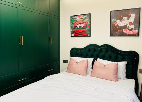 a bedroom with green cabinets and a bed with pink pillows at 2-bedroom Doji apartment in hai phong in Hai Phong