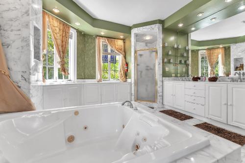 a white bath tub in a bathroom with windows at Young Mansion Steps To The Beach in Hollywood