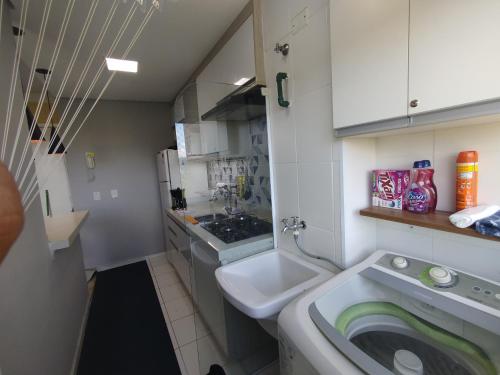 コチアにあるApartamento Ao lado Animalia Park com piscina e estacionamentoの洗面台と洗濯機を備えた小さなバスルーム