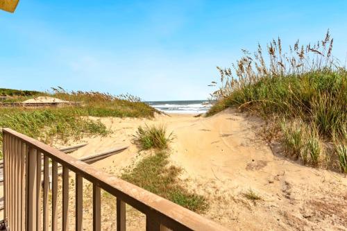 a sandy beach with a wooden railing and the ocean at DL104 - Dune's Watch in Nags Head