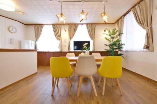 a dining room with a table and four yellow chairs at cuculu MAEJIMA 7F in Tomari