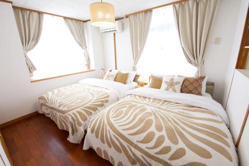 two beds sitting in a room with windows at cuculu MAEJIMA 7F in Tomari