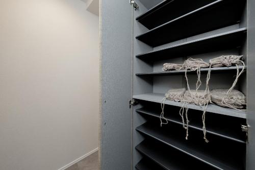 a closet with black shelves with ropes at ZAITO Waseda Terra Hotel in Tokyo