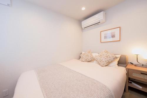 a white bedroom with a bed and a night stand at ZAITO Waseda Terra Hotel in Tokyo