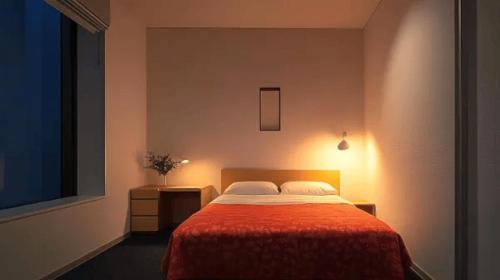 a bedroom with a bed with a red blanket at Nagoya Premium Hotel in Inazawa