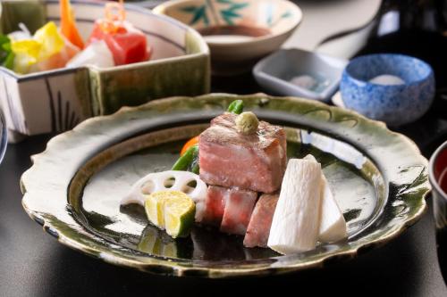 a plate of food with meat and fruit on a table at Oni no Sumika in Izu