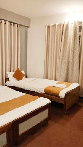 two twin beds in a room with curtains at Hotel Sakura Mountain view Near Darjeeling Toy Train Station in Darjeeling