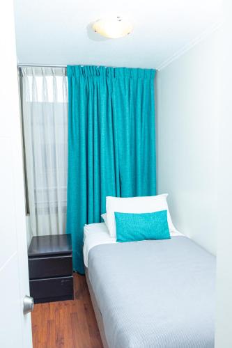 a bedroom with a bed with a blue curtain at Departamentos Amoblados Torre Tagle in Santiago