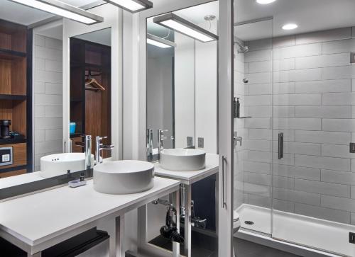 a bathroom with two sinks and a shower at Aloft Raleigh in Raleigh