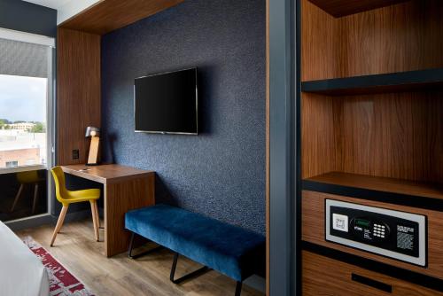 a room with a desk and a tv on a wall at Aloft Raleigh in Raleigh