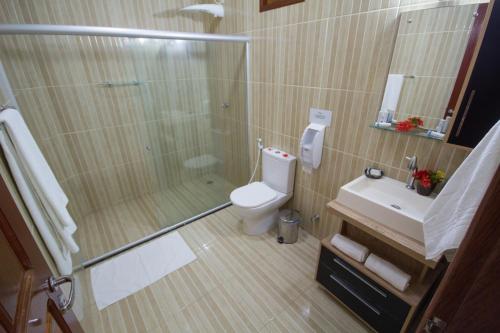 a bathroom with a shower and a toilet and a sink at Pousada Venezia Tropicale in Japaratinga