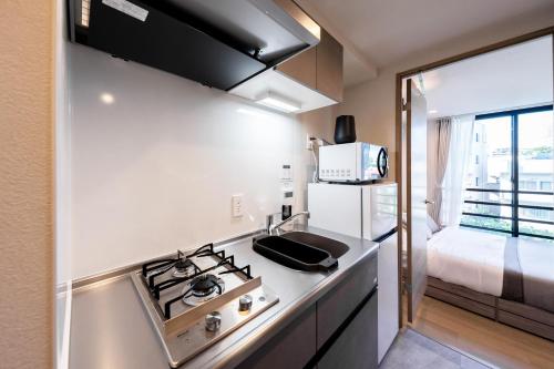 a kitchen with a stove and a sink and a bed at ZAITO Waseda Terra Hotel in Tokyo