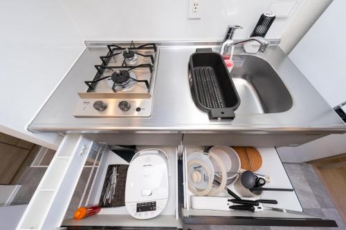 a kitchen with a stove and a sink at ZAITO Waseda Terra Hotel in Tokyo