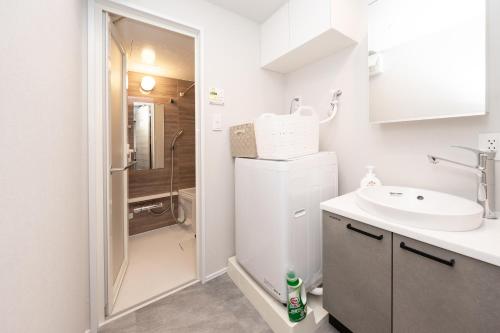 a white bathroom with a sink and a refrigerator at ZAITO Waseda Terra Hotel in Tokyo