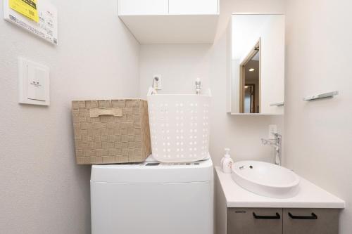 a white bathroom with a sink and a toilet at ZAITO Waseda Terra Hotel in Tokyo