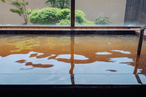 a pool of muddy water in a room with a window at tanoshic resort 西紀荘 in Ubara