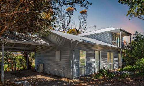 a gray house with a garage and trees at Bungala Cottage 28 Jetty Road in Normanville