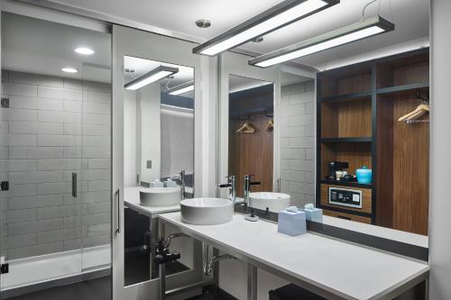 a bathroom with two sinks and two mirrors at Aloft Raleigh in Raleigh