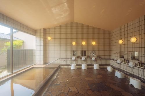 a bathroom with four urinals on a tiled wall at tanoshic resort 西紀荘 in Ubara