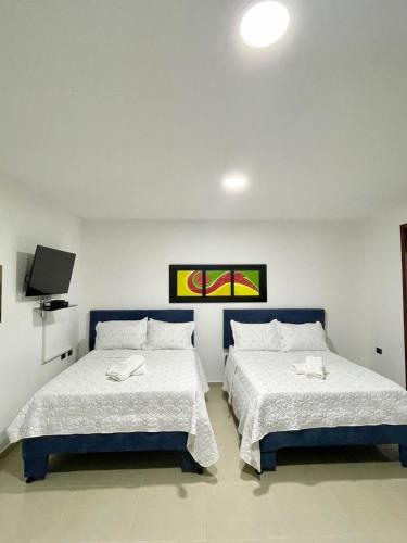 a bedroom with two beds with white sheets and a tv at Apartahotel MKS Caribe in San Andrés
