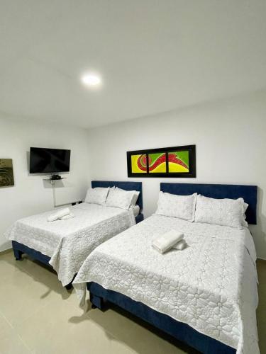 a bedroom with two beds and a flat screen tv at Apartahotel MKS Caribe in San Andrés